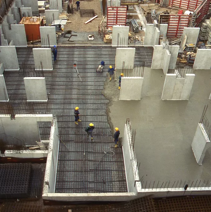 Der Blick von oben auf eine Baustelle. Die grauen Betonwände sind errichtet, rechts der Bildmitte wird der Betonboden gegossen.